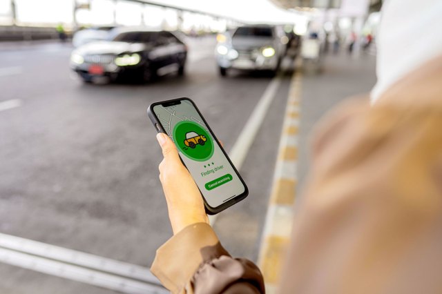 An image of a person holding up their phone with a ride share app open