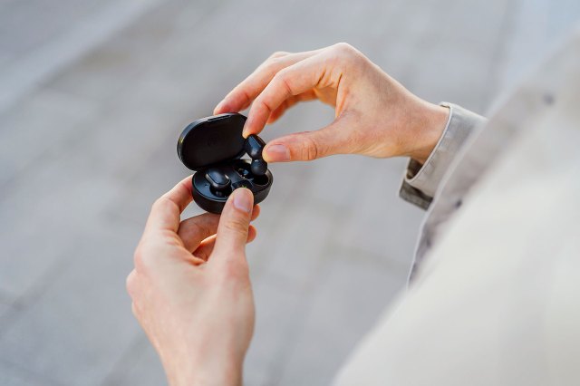 An image of a person putting an earbud into a headphone case