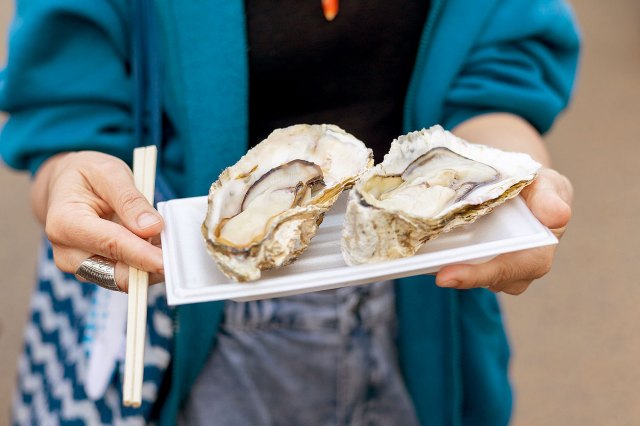 An image of a person holding a plate with two oysters