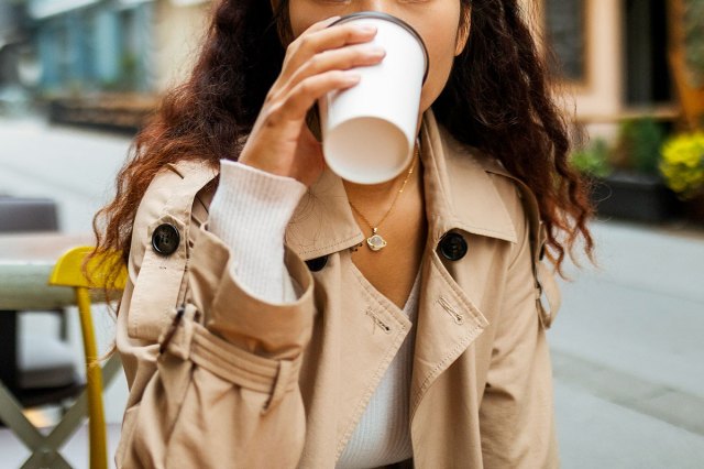 An image of a woman drinking a to-go cup of coffee
