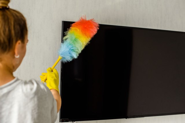 An image of a woman dusting a TV