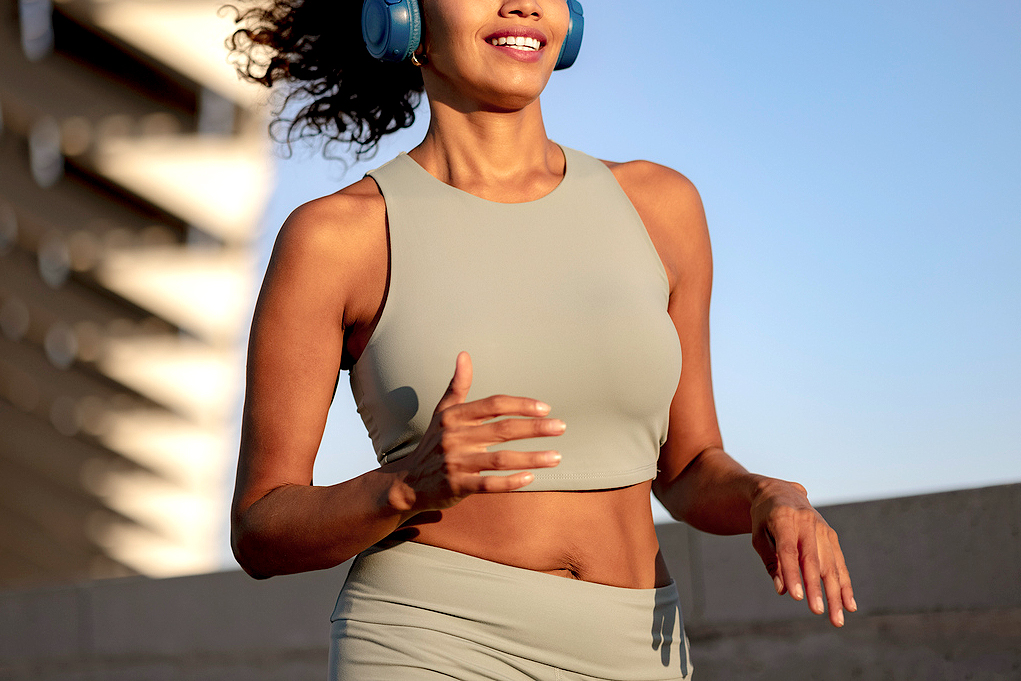 An image of a woman in workout clothes and headphones outside