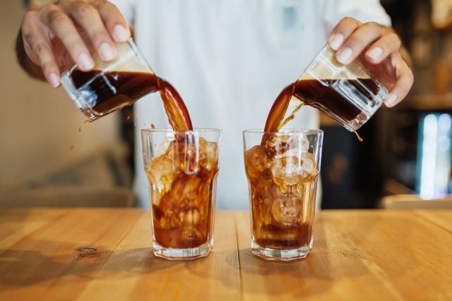 An image of a person pouring two shots of espresso into glasses of ice