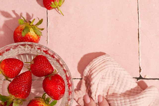 An image of a bowl of strawberries on pink tile