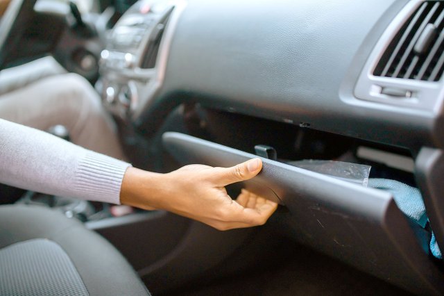 An image of a woman opening the glove compartment