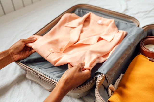 An image of a person placing a folded shirt in a suitcase