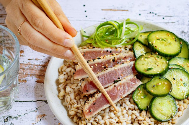 An image of a bowl of brown rice, tuna, and cucumbers