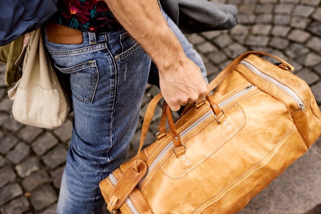 An image of a person holding a leather duffle bag
