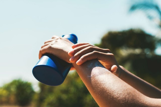 An image of a hand rubbing sunscreen on an arm