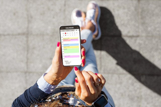 An image of a person holding a phone with the calendar app open