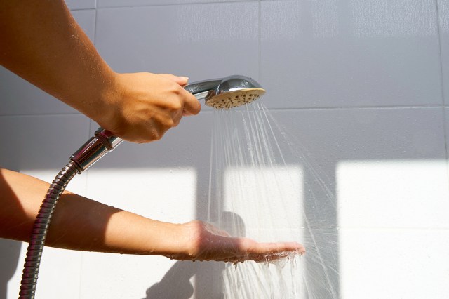 A person sprays water from a shower attachment over their hand