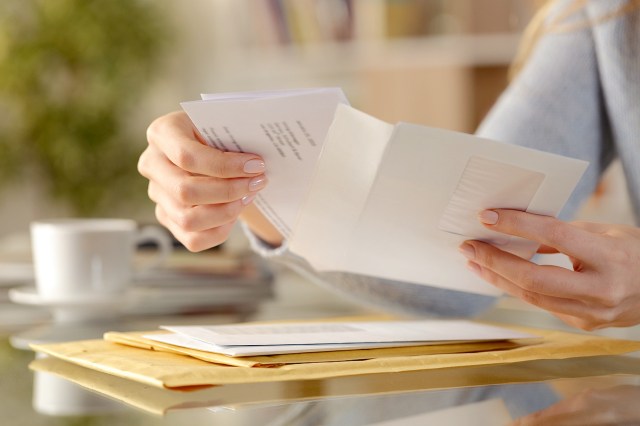 An image of a woman putting a letter in an envelope