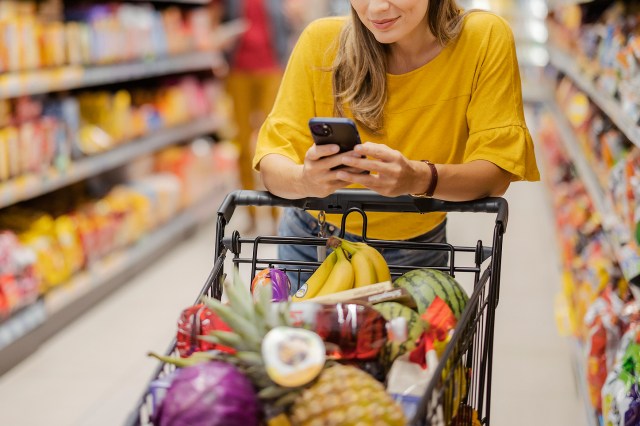 An image of a woman on her phone while at the grocery store