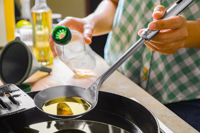 An image of a person holding a ladle above a cast-iron pan