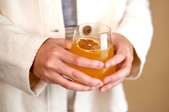 An image of a person holding a glass of kombucha