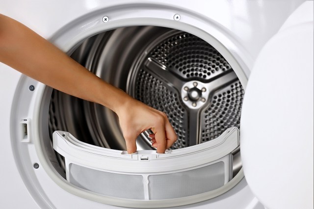 An image of a person pulling the lint trap out of a dryer