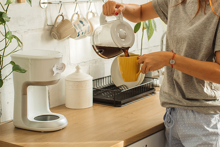 An image of a woman pouring a mug of coffee