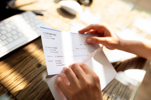 An image of a person putting a check into an envelope