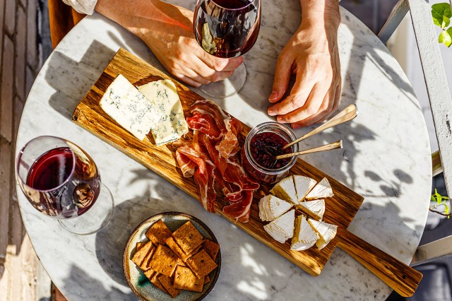 An aerial view of a table with a board of cheese and meets and glasses of wine