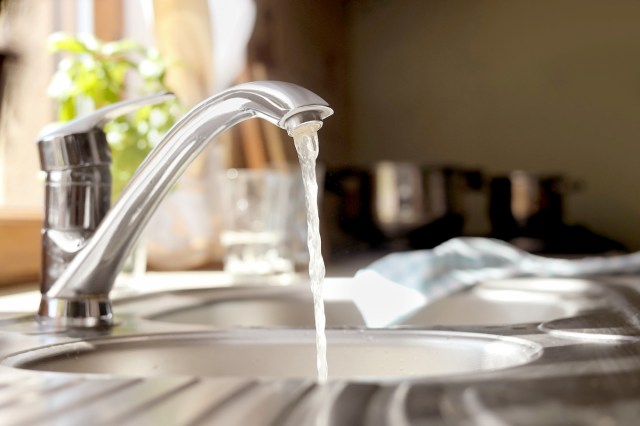 An image of a kitchen sink with the faucet on