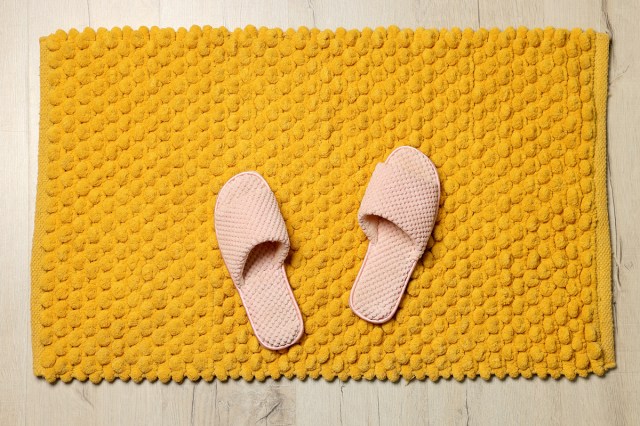 An image of pink slippers on a yellow bath mat
