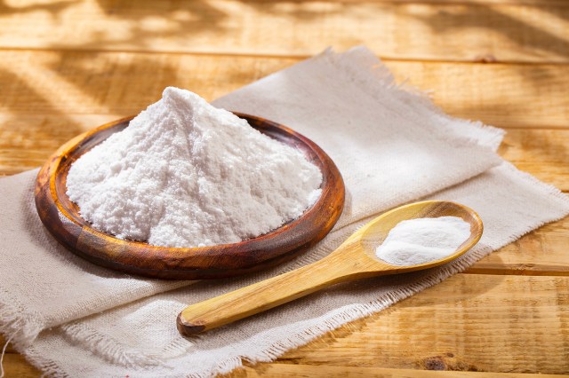 An image of a wooden bowl of white powder and a wooden spoon with white powder