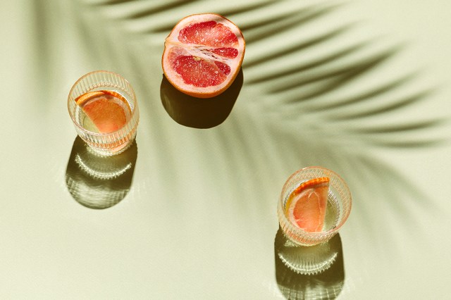 An image of two glasses with slices of citrus in them and a half of grapefruit