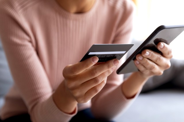 An image of a woman holding her phone and a credit card
