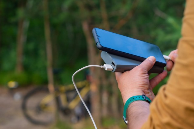 An image of a person holding a phone and a portable charger