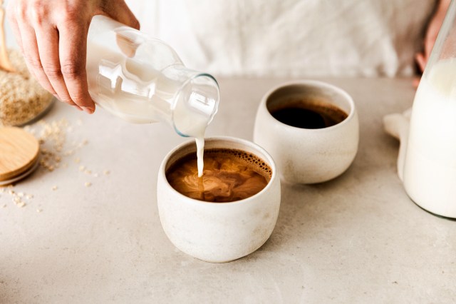 An image of a person pouring milk into a mug of coffee