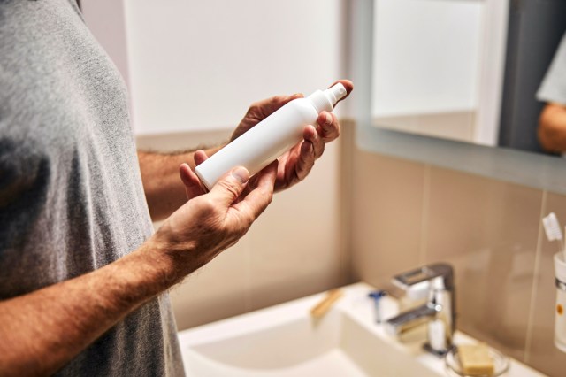 An image of a person holding a small white spray bottle