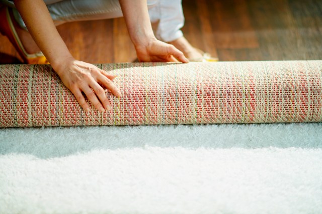 An image of a person unrolling a rug
