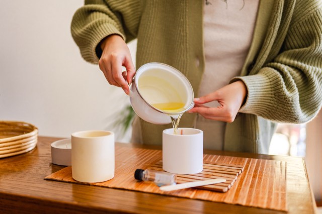 An image of a person pouring candle wax into a white candle jar