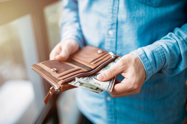 An image of a person taking cash out of a brown wallet