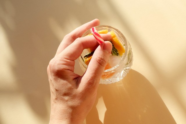 An image of a person putting a red-and-white straw in a glass