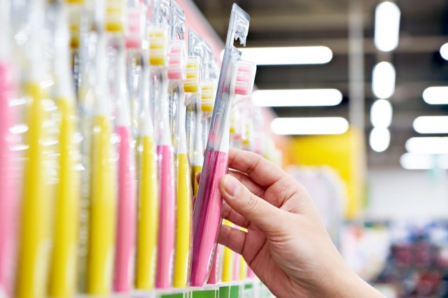 An image of a person pulling a toothbrush off a store shelf