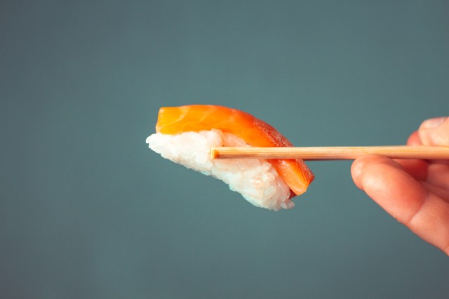 Sushi held with a pair of chopsticks