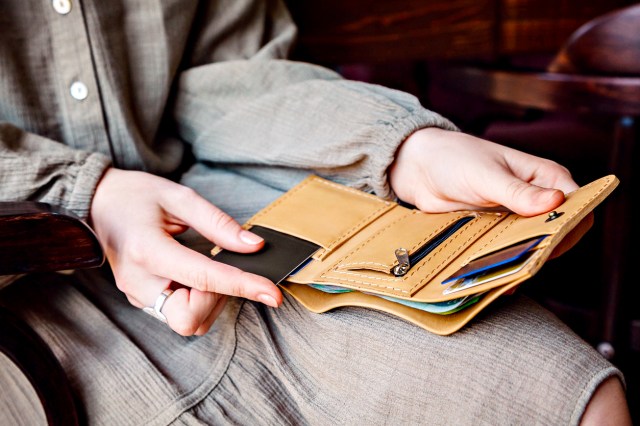 An image of a woman putting a credit card into a wallet