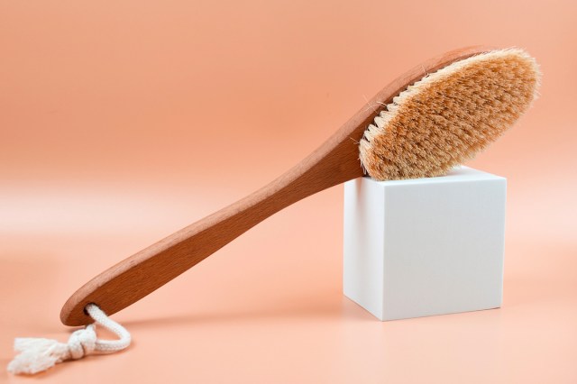 An image of a back brush resting on a white cube against a peach background