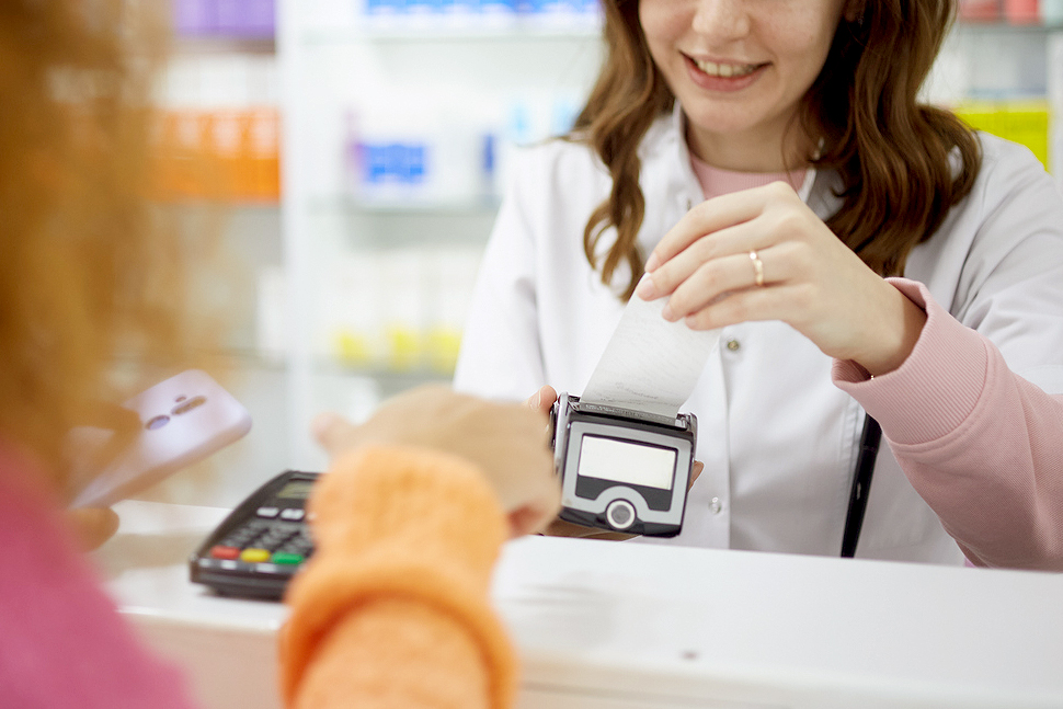 An image of a pharmacist ripping a receipt out of credit card machine