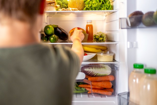 An image of a man grabbing fruit from the fridge