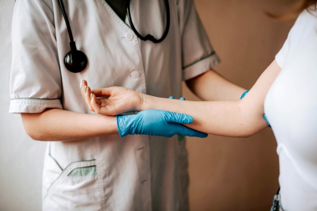 An image of a doctor holding a woman's arm