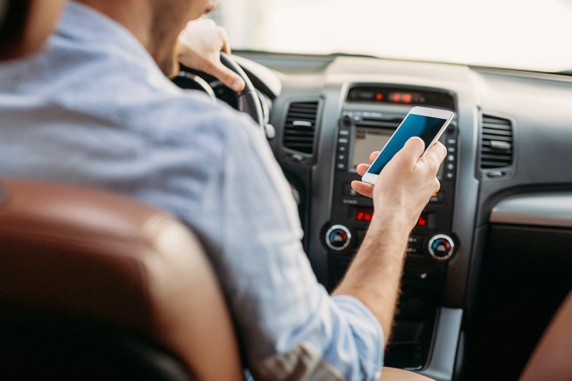 An image of a man holding a phone in a car