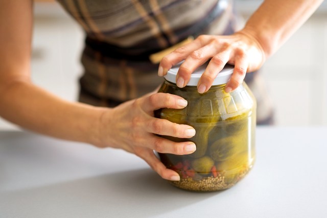 An image of a person opening a jar of pickles