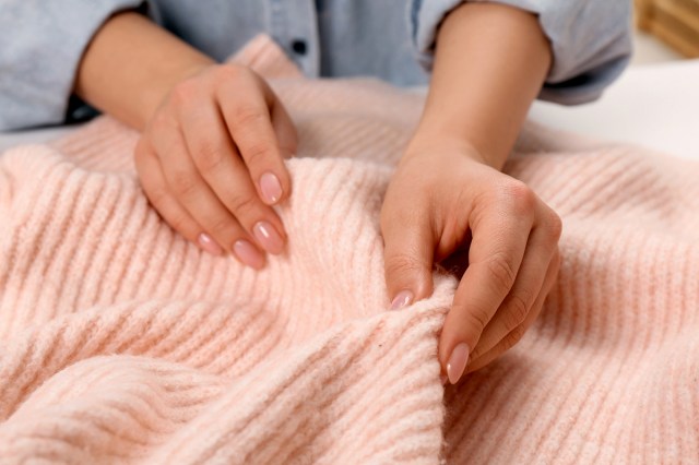 An image of two hands on a pink sweater