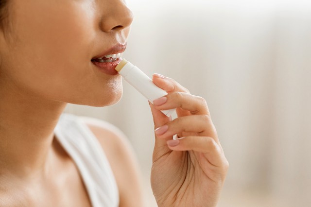An image of a woman putting on chapstick