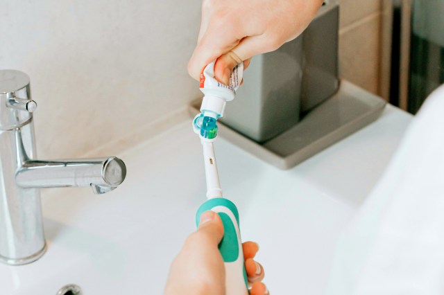 An image of a person squeezing toothpaste onto a toothbrush