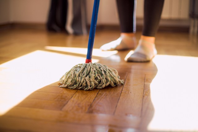 A close-up image of a person mopping a wooden floor