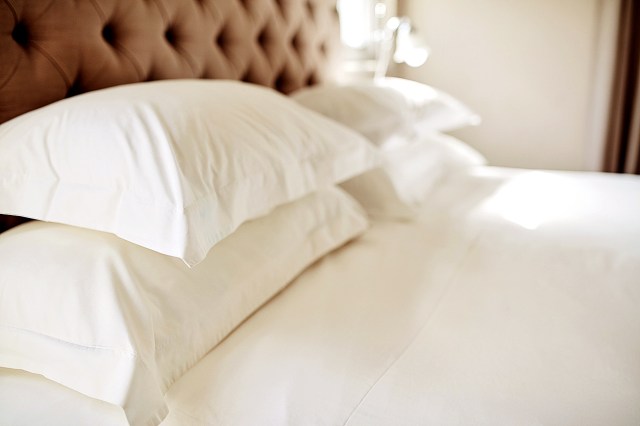An image of a bed with white pillows and sheets
