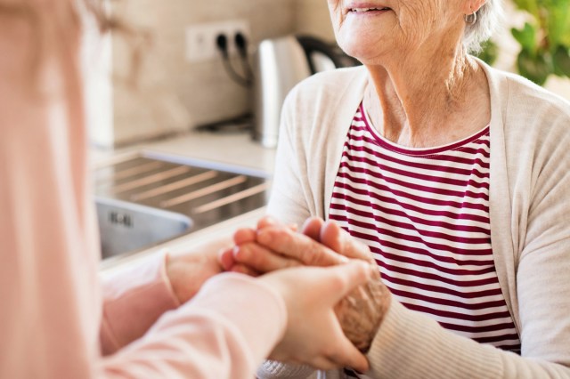 An image of a woman holding the hands of an elderly woman